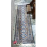 Modern Eastern runner with ten blue lozenge shaped guls to the madder ground 242cm x 76cm