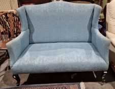 Edwardian wingback two-seat sofa in pale blue upholstery, with cabriole front legs to castors