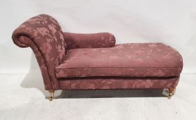 Modern chaise longue in purple foliate upholstery, on turned legs to brass castors