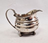 Georgian silver milk jug, the handle embossed with fruits and vine, ribbed body, ball feet, London