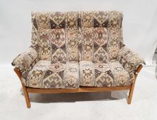 Ercol two-seater sofa and footstool in cream ground patterned upholstery