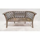 Wooden garden bench with curved arms, splayed legs and cast iron trellis inserts