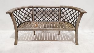 Wooden garden bench with curved arms, splayed legs and cast iron trellis inserts