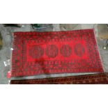 Eastern red ground rug with four central motifs, in red and black, 175cm x 90cm