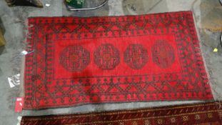 Eastern red ground rug with four central motifs, in red and black, 175cm x 90cm