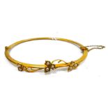 Gold-coloured metal and seedpearl bangle, hinged and set with three trios of seedpearls in leafy