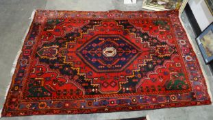 Eastern rug, the blue ground with central hexagonal motif, on a red ground field with bird