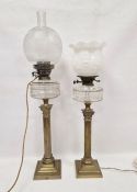 Two similar brass Corinthian column oil lamps with clear glass faceted reservoirs, converted to