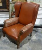 Early 20th century wingback armchair in brown leather upholstery, on turned front legs