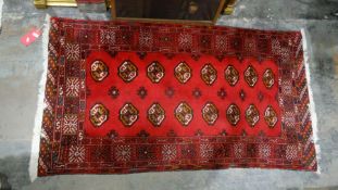 Iranian balouch rug, the red ground field with 16 elephant foot guls and decorative border, 168cm