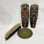 Two carved and painted wooden tribal masks, a pair of vintage ice skates, a carved elephant train on