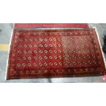 Eastern rug with eighty repeated elephant foot guls on a red ground field, to a stepped border,