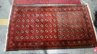 Eastern rug with eighty repeated elephant foot guls on a red ground field, to a stepped border,