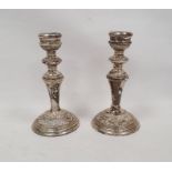 Pair of 1920's silver weighted candlesticks, relief decorated on a circular base, Birmingham 1924,