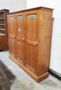 20th century pine three-door wardrobe with moulded cornice above three panelled doors, over plinth