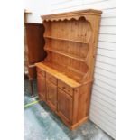 Pine dresser with moulded cornice above two shelves, on curved rectangular base with three drawers