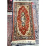 Modern eastern style red ground rug with central floral medallion and floral border 155cm x 78.5cm