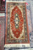 Modern eastern style red ground rug with central floral medallion and floral border 155cm x 78.5cm