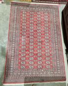 Eastern style red rug with four rows of seventeen elephant foot guls with multiple geometric borders