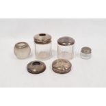 Two silver lidded glass jars, a silver-mounted candlestick holder, two loose silver lids and a