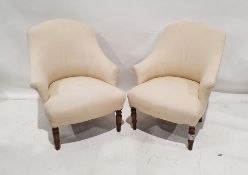 Pair of early 20th century low armchairs with cream-coloured upholstery on turned front legs