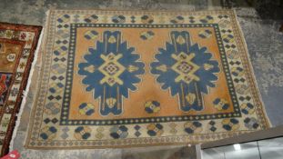 Pink ground rug with two central blue ground motifs, on a foliate border, 193cm x 134cm