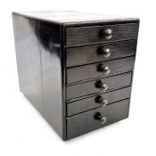 A black tabletop collector's cabinet of six drawers, 20.5cm wide and 28.5cm high
