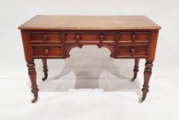 19th century mahogany desk, the central drawer above arched carved scrollwork decoration, flanked by