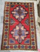 New Baluchi red ground rug with two floral medallions surrounded by multiple geometric shapes and
