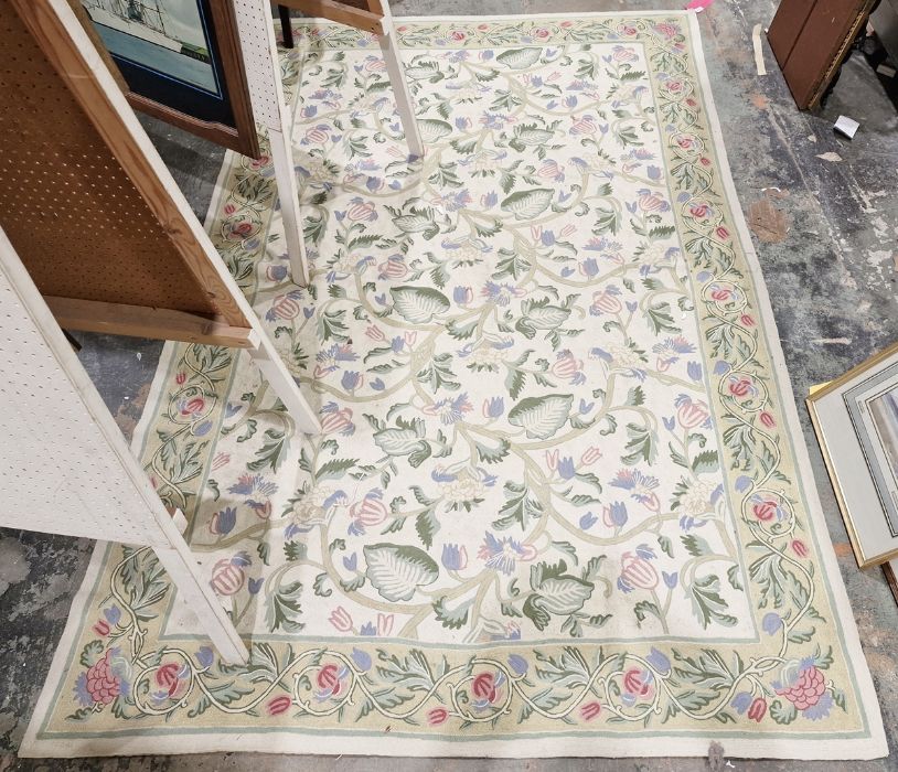 Large needlework cream ground rug, the central scrolling floral pattern with floral border 244 x