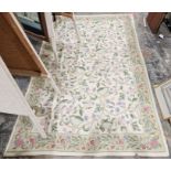 Large needlework cream ground rug, the central scrolling floral pattern with floral border 244 x