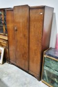 Dark stained oak wardrobe with flowerhead moulded frieze above rounded central door, enclosing a