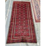 North East Persian Meshed Belouch red ground rug with two rows of eleven lozenge medallions enclosed