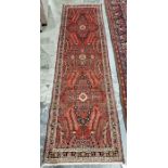 North West Persian Malayer red ground runner with one row of three floral medallions enclosed by