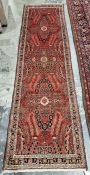 North West Persian Malayer red ground runner with one row of three floral medallions enclosed by