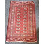 Eastern style red ground rug with two rows of nine elephant foot guls to multiple geometric and