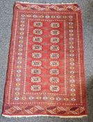 Eastern style red ground rug with two rows of nine elephant foot guls to multiple geometric and