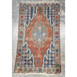 Eastern style red ground rug with central geometric medallion enclosed by floral pattern to a