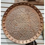 Large circular copper tray with embossed decorations and bosses around the interior rim 36cms diam