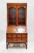 Oak bureau bookcase with glazed double doors above panelled fall front, revealing two drawers and