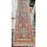 Eastern red ground runner with five lozenge medallions enclosed by geometric and floral shapes,