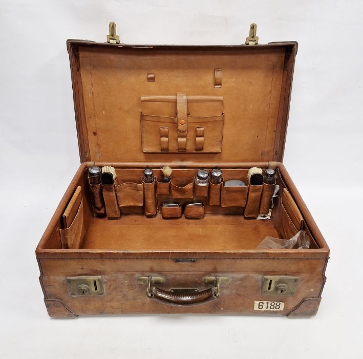 Large leather suitcase with part fitted interior of bottles, brushes, mirrors, etc, with name plaque
