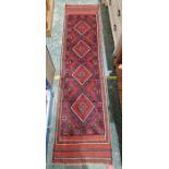 Meshwani red ground wool runner with one row of four diamond medallions and multiple geometric