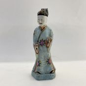 Chinese glazed porcelain figure of a smiling man in pale blue and floral medallion robe, 20cm high