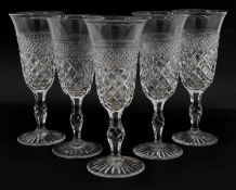 A set of five hand cut lead crystal champagne flutes with cross hatched design, star cut bases and