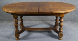 An antique style Ipswich oak extending dining table with two extra leaves on baluster turned