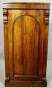 An early Victorian rosewood pier cabinet with arched panel door enclosing shelves on plinth base.