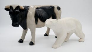 A glazed ceramic cow along with a resin sculpture of a polar bear. H.23cm