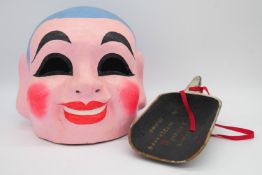 Two Oriental masks, one painted carved wood and one of Buddha made of papier mache. H.27cm