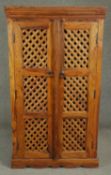 An Indian teak bookcase with lattice panelled doors on shaped bracket feet. H.135 W.75 D.36cm